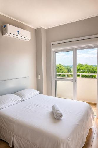 a bedroom with a large white bed and a window at Apartamento - 2 Quartos * Completo * Central in Bento Gonçalves