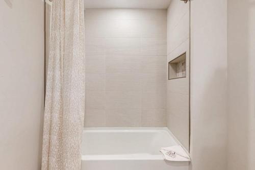 a white bathroom with a tub and a shower curtain at Skywalk Flats Escape in Silverthorne