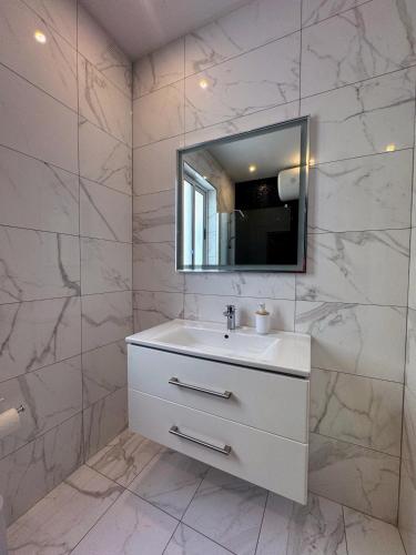 a white bathroom with a sink and a mirror at Marsaxlokk Harbour View Apartment in Marsaxlokk