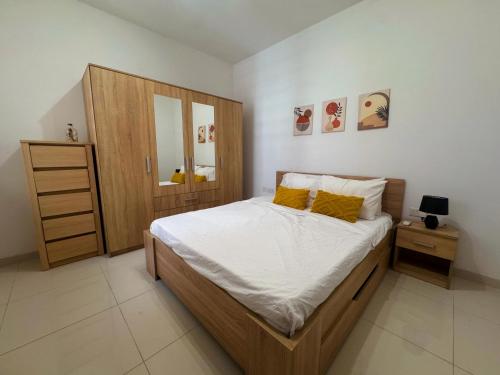 a bedroom with a large bed and a wooden cabinet at Marsaxlokk Harbour View Apartment in Marsaxlokk