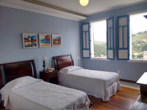 a bedroom with two beds and two windows at Hotel Pousada Minas Gerais in Ouro Preto