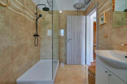 a bathroom with a shower and a tub and a sink at Small stone house in Ližnjan