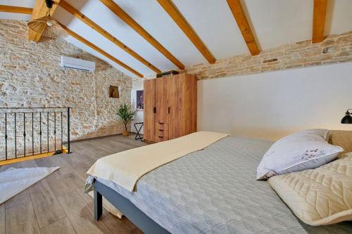 a bedroom with a bed and a brick wall at Small stone house in Ližnjan