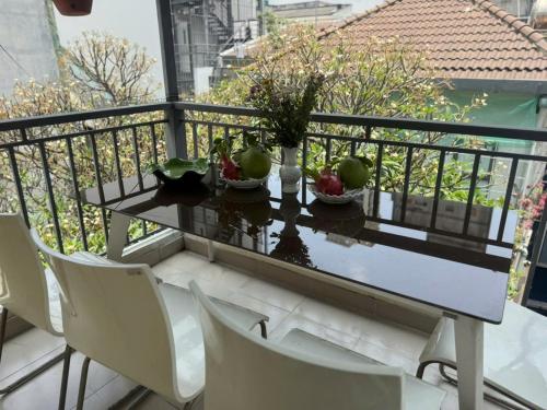 a table and chairs on a balcony with fruit on it at The New Chapter Hostel in Ho Chi Minh City