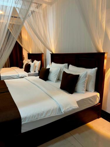a bedroom with two beds with white sheets and curtains at Peak Blooms Ella in Ella