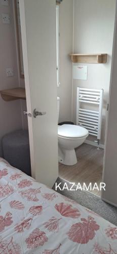 a bathroom with a bed and a toilet in it at Kazamar in East Mersea