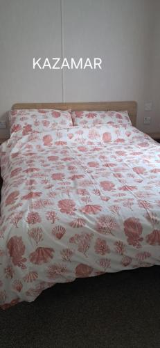 a bed with a white and red bedspread on it at Kazamar in East Mersea