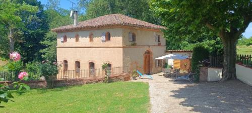 a small house with a fence in a yard at Le moulin de Christine in Saint-Nauphary