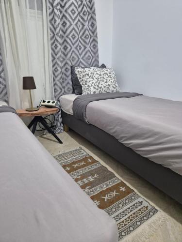 a bedroom with two beds and a table with a lamp at L'ancienne menuiserie in Tabarka