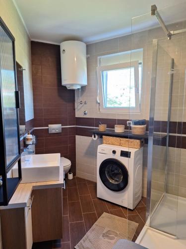 a bathroom with a washing machine and a sink at Apartment Sunrise in Kunjići