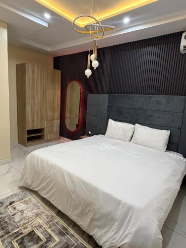 a bedroom with a large white bed with a ceiling at Modern 2 BR apartment in Lekki