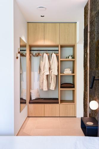 a closet with wooden cabinets and white clothes at B&Biotope in Heusden