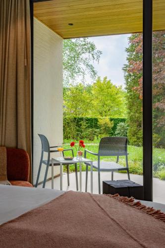 a bedroom with a bed and a table and chairs at B&Biotope in Heusden
