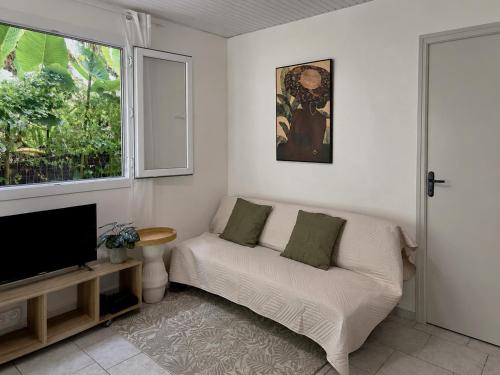 a living room with a couch and a television at Kay Canou - Vue jardin tropical - Calme & nature in Le Robert