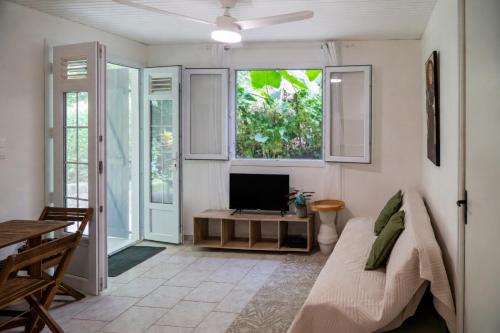 a living room with a bed and a tv in it at Kay Canou - Vue jardin tropical - Calme & nature in Le Robert