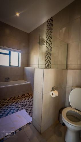 a bathroom with a toilet and a bath tub at Judith & Sylvester Hideaway in Victoria Falls