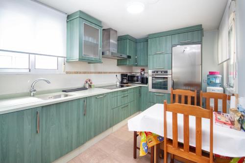 a kitchen with green cabinets and a table and chairs at AG Piso Vazquez Parga Carballo in Carballo