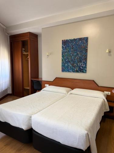 two beds in a bedroom with a painting on the wall at Pensión La Salve in Bilbao