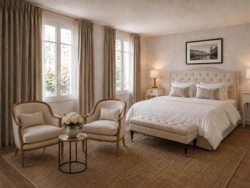 a bedroom with a white bed and two chairs at Château Alto Cormeil in Saint-Émilion