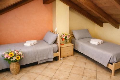 two beds in a room with flowers in a room at Casa Maria in Pettenasco