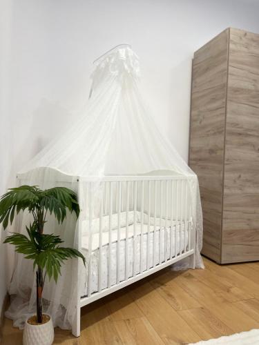 a white crib with a canopy in a room with a plant at Studio Yas Central Arad in Arad