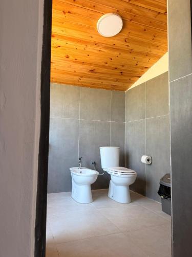 a bathroom with a toilet and a wooden ceiling at Perseku GuestHouse in Shirokë