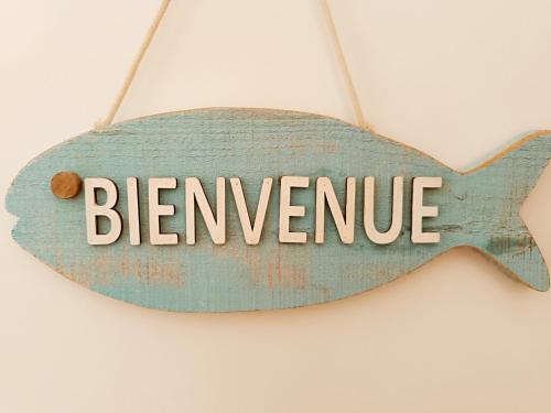 a sign with the word benvenuto hanging on a wall at Les pieds dans l'eau in Mèze