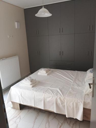 a bedroom with a white bed with gray cabinets at stavros house byzarkco in Porto Rafti