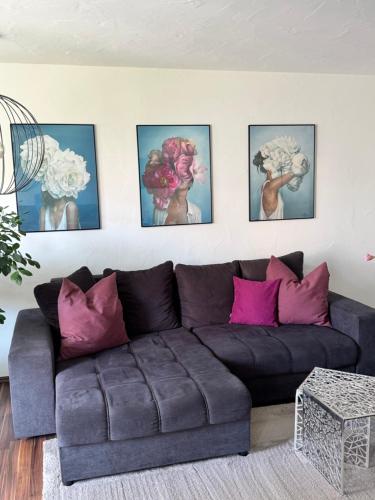 a living room with a couch and four paintings on the wall at Ferienwohnung Homburger - Immenstaad am Bodensee in Immenstaad am Bodensee
