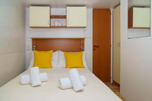 a bedroom with a bed with yellow and white pillows at Lavender Mobile Houses in Pakoštane