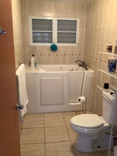 a bathroom with a white tub and a toilet at Cozy & comfortable crib in Carolina