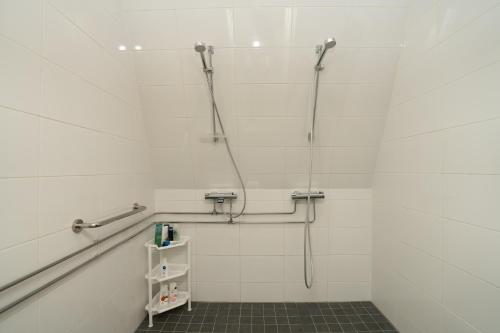 a white bathroom with a shower and a shelf at Majatalo Mäntän Kuusela in Mänttä