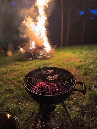 a barbecue grill with a fire in the background at Sanovia Glamping Max in Reczpol
