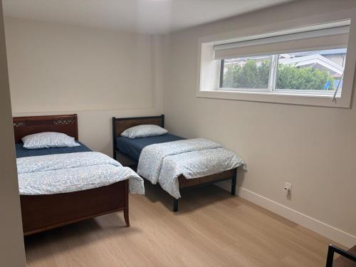 two beds in a room with a window at Cozy home in Burnaby