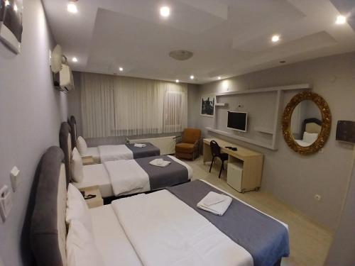 a hotel room with three beds and a television at Pera City Otel in Samsun