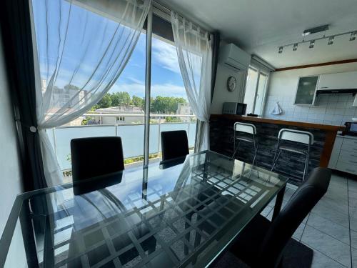 a glass table and chairs in a room with a window at Appartement Port Marianne Montpellier in Montpellier