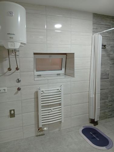 a bathroom with a flat screen tv and a shower at Apartman Ema in Bihać