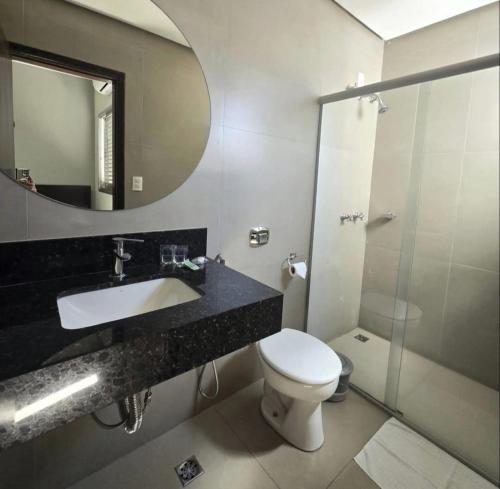 a bathroom with a toilet and a sink and a shower at Hotel Mohallem in Passos