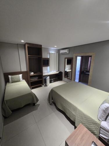 a hotel room with two beds and a table at Hotel Mohallem in Passos