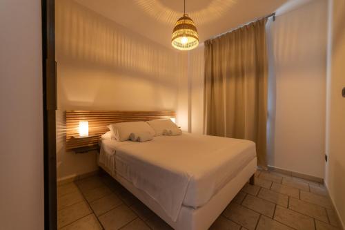 a bedroom with a large white bed with a light at Casa Pescoluse 50m dal Mare in Marina di Pescoluse