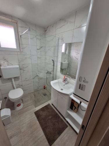 a white bathroom with a sink and a toilet at Apartmani Milojević in Boljevac