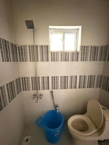 a bathroom with a toilet and a blue bucket at Ameer lodge in Hunza Valley