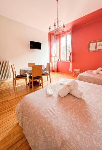 a bedroom with two beds and a dining room with a table at Les Suites du Quai in Montmélian
