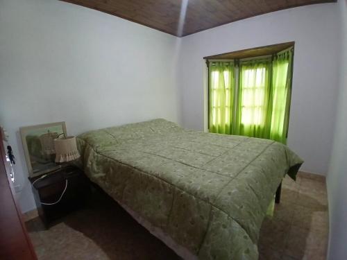 a bedroom with a green bed and a window at Cabañas amanecer alegre in Salta