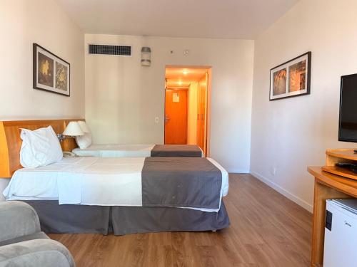 a hotel room with two beds and a flat screen tv at Hotel & Residence Alphaville in Barueri