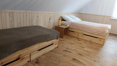 a bedroom with two beds and a wooden floor at Dom nad jeziorem Serwy in Serwy
