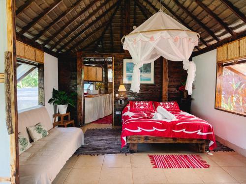 a bedroom with a bed and a couch in a room at Fare Hau Lodge in Tahaa