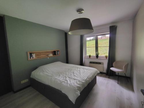 a bedroom with a bed and a window and a chair at La clé des champs chambre d'hôtes in Theux