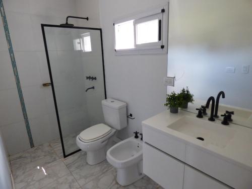 a white bathroom with a toilet and a sink at Almahue in Quebrada de los Pozos