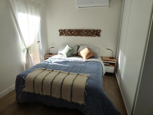 a bedroom with a bed with a blue blanket and a window at Almahue in Quebrada de los Pozos